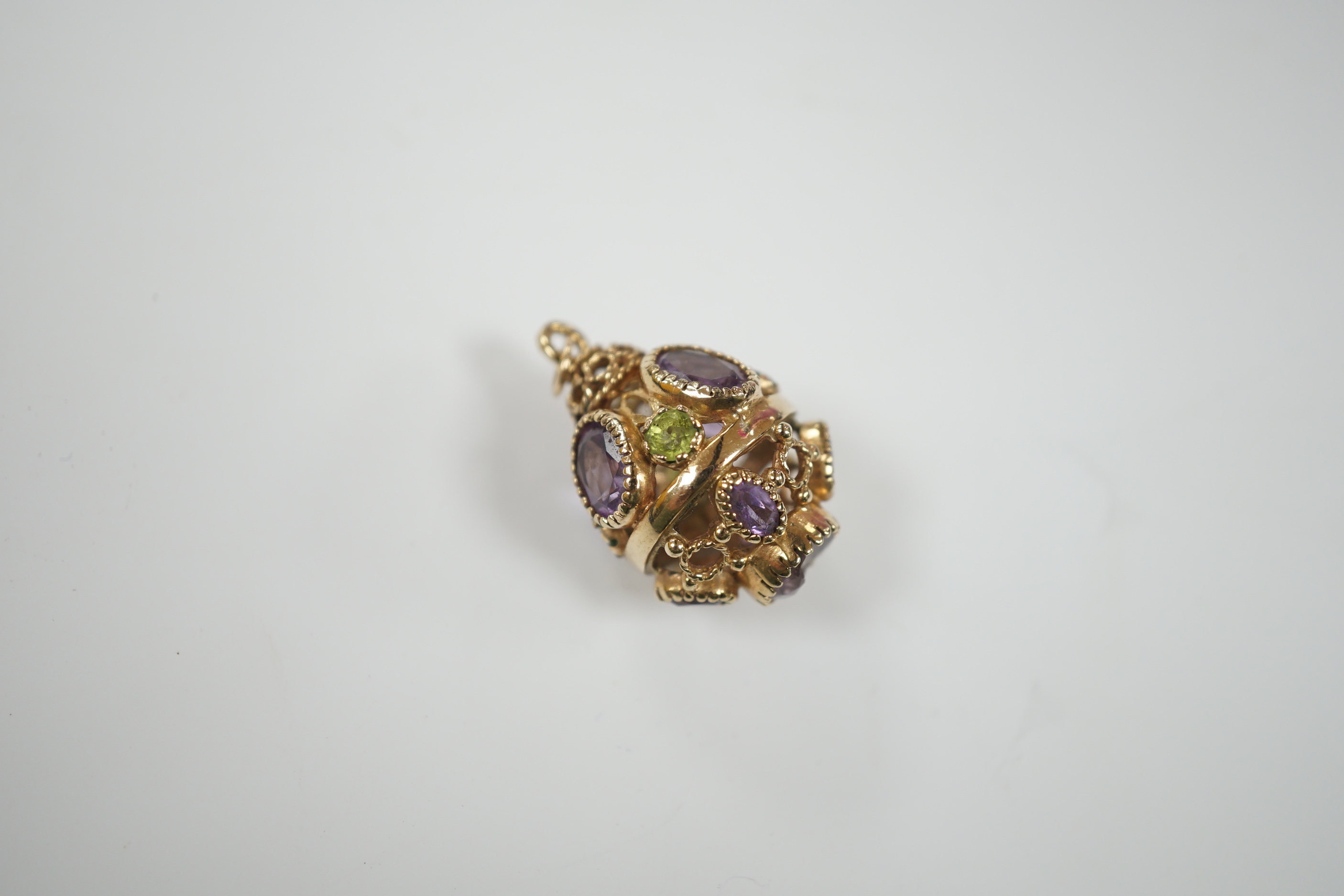 A modern 9ct gold, amethyst and peridot set pendant, or pierced spherical form, 25mm, gross weight 7.5 grams.